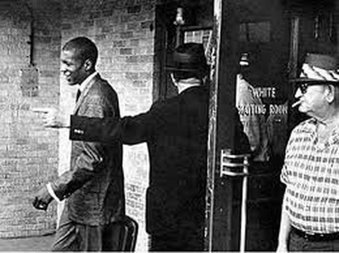 Black man walking past a segregated White Waiting Room